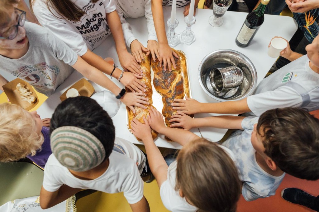 Children gathering around Challah bread for Shabbat